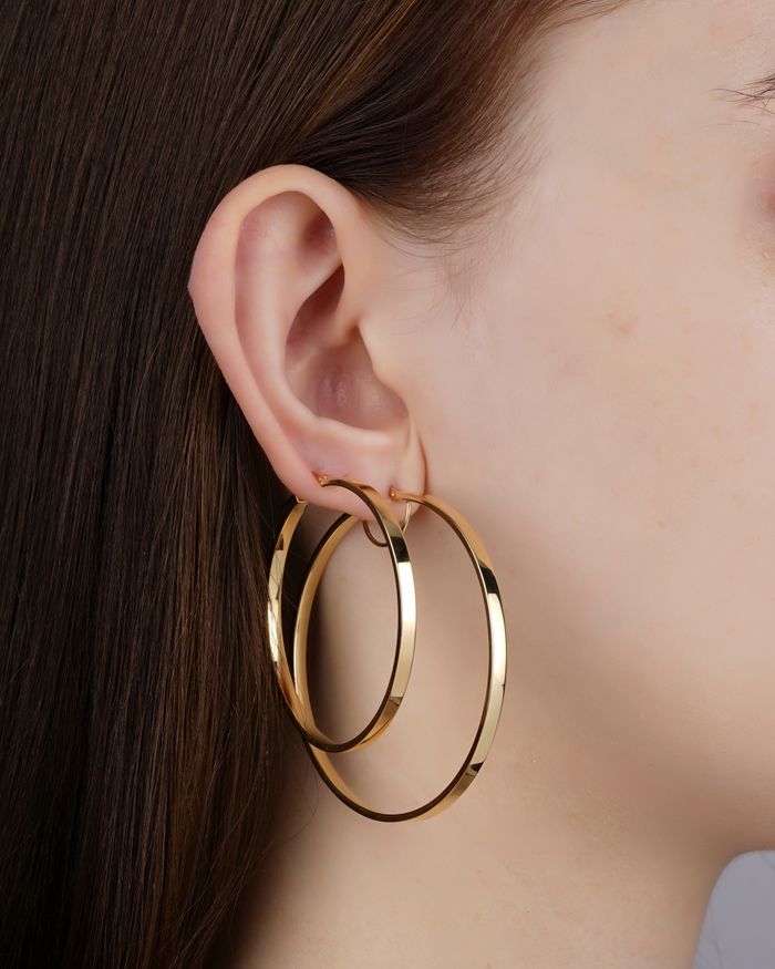 Elegant close-up of a woman's ear adorned with large gold hoop earrings, showcasing jewelry fashion.