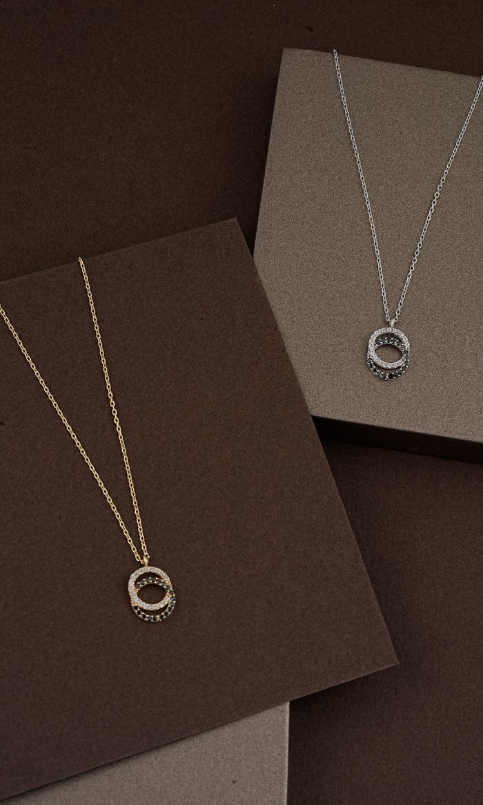 Top-down view of elegant gold and silver necklaces on a textured background.